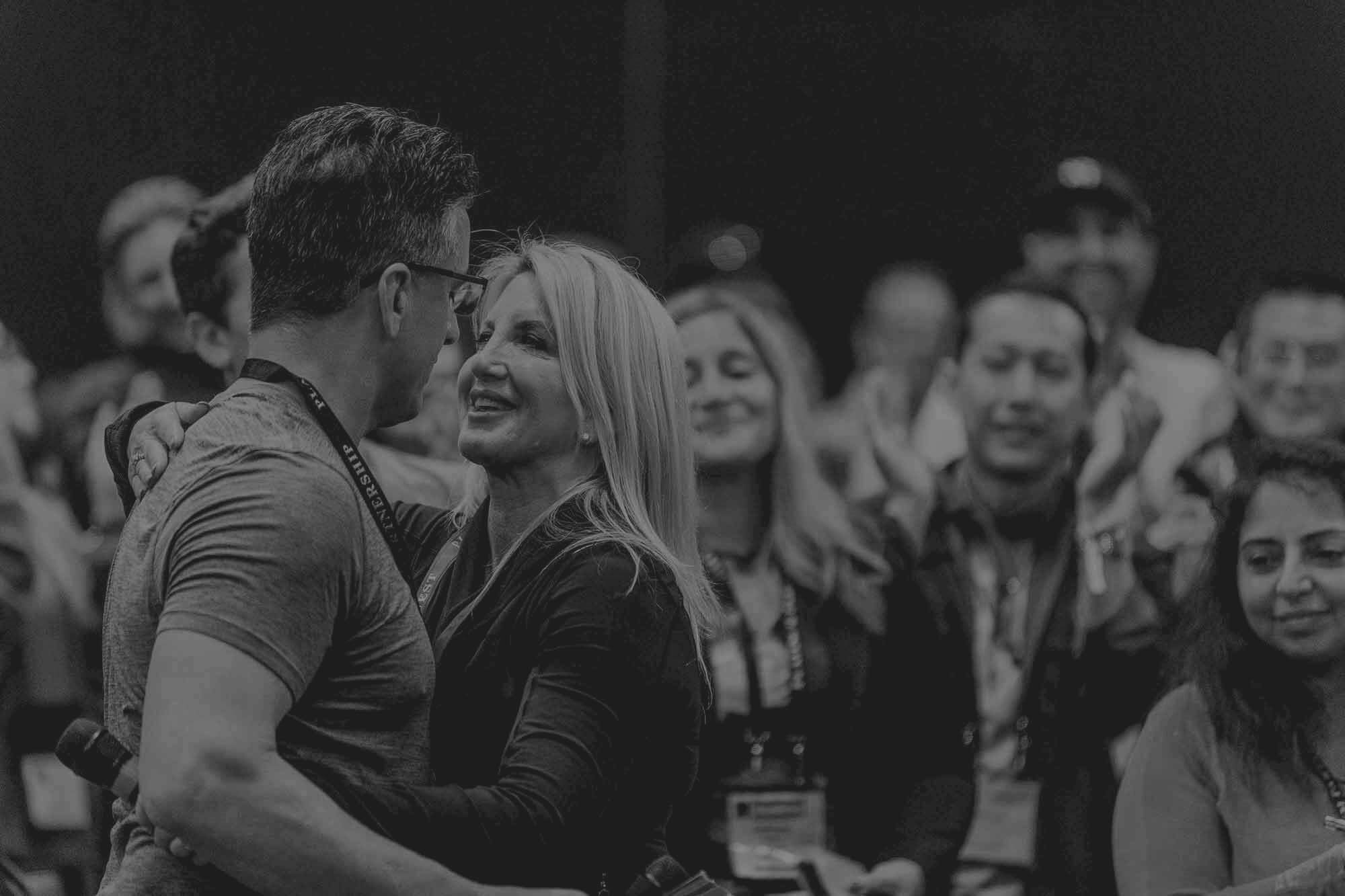 a man and a woman are hugging each other in front of a crowd of people .