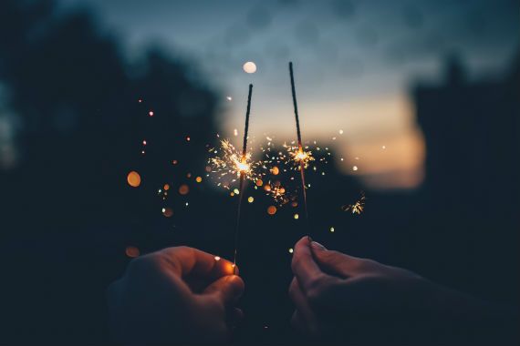 a person is holding two sparklers in their hands at night .