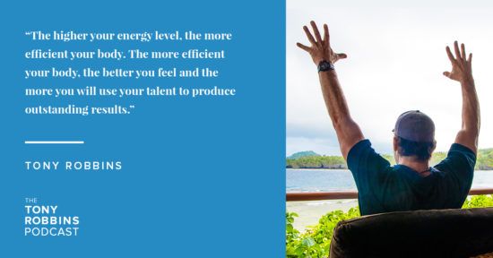 Tony Robbins sitting on a balcony with his arms in the air