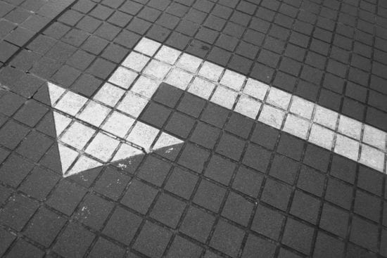 a black and white photo of an arrow painted on the sidewalk .