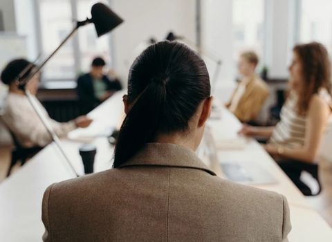 a woman is sitting at a table in front of a group of people .