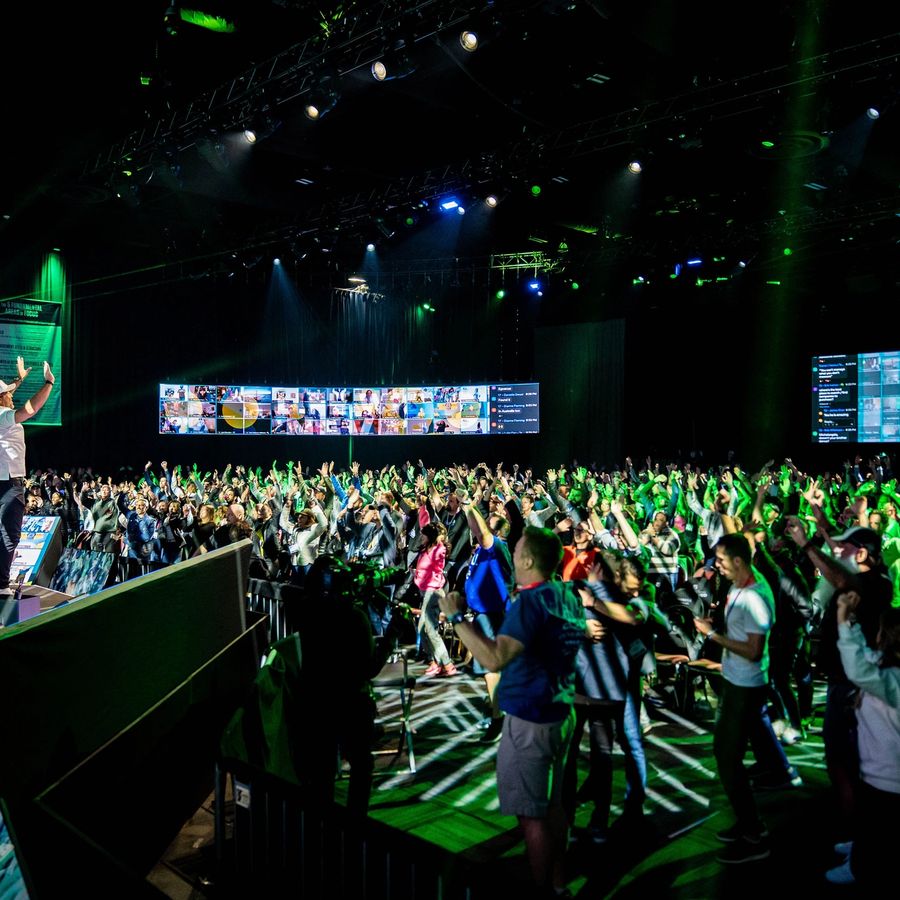 a man is standing on a stage in front of a crowd of people at an event