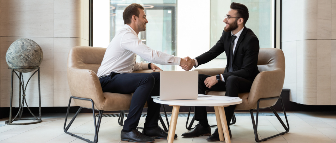 two men are shaking hands while sitting on a couch