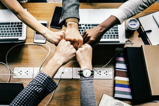 a group of people are putting their fists together on a table .