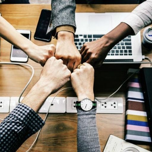 a group of people are putting their fists together on a table .