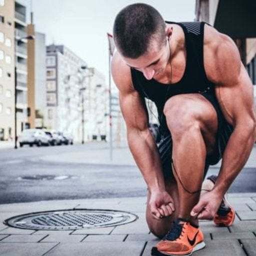a man is tying his shoes on the sidewalk .
