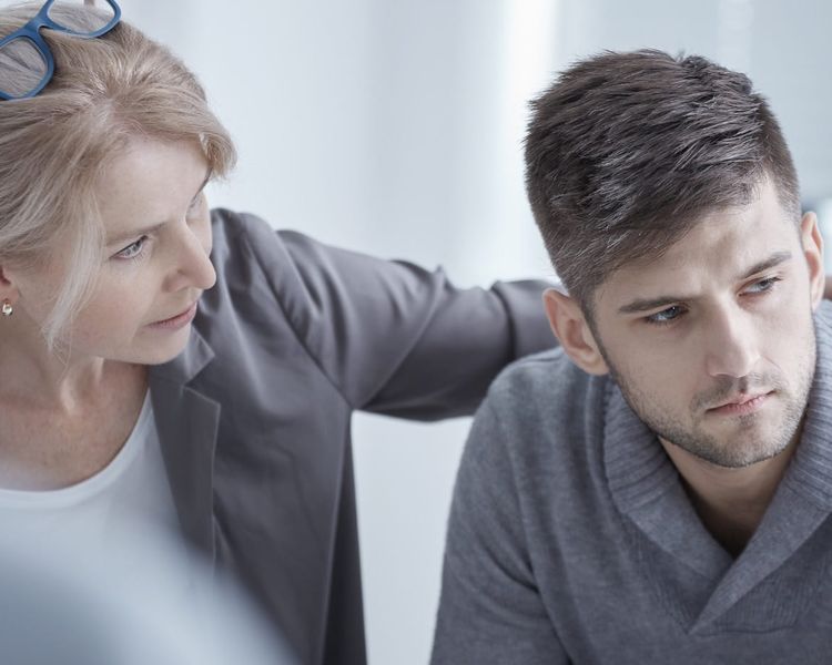a woman is comforting a man during a therapy session .