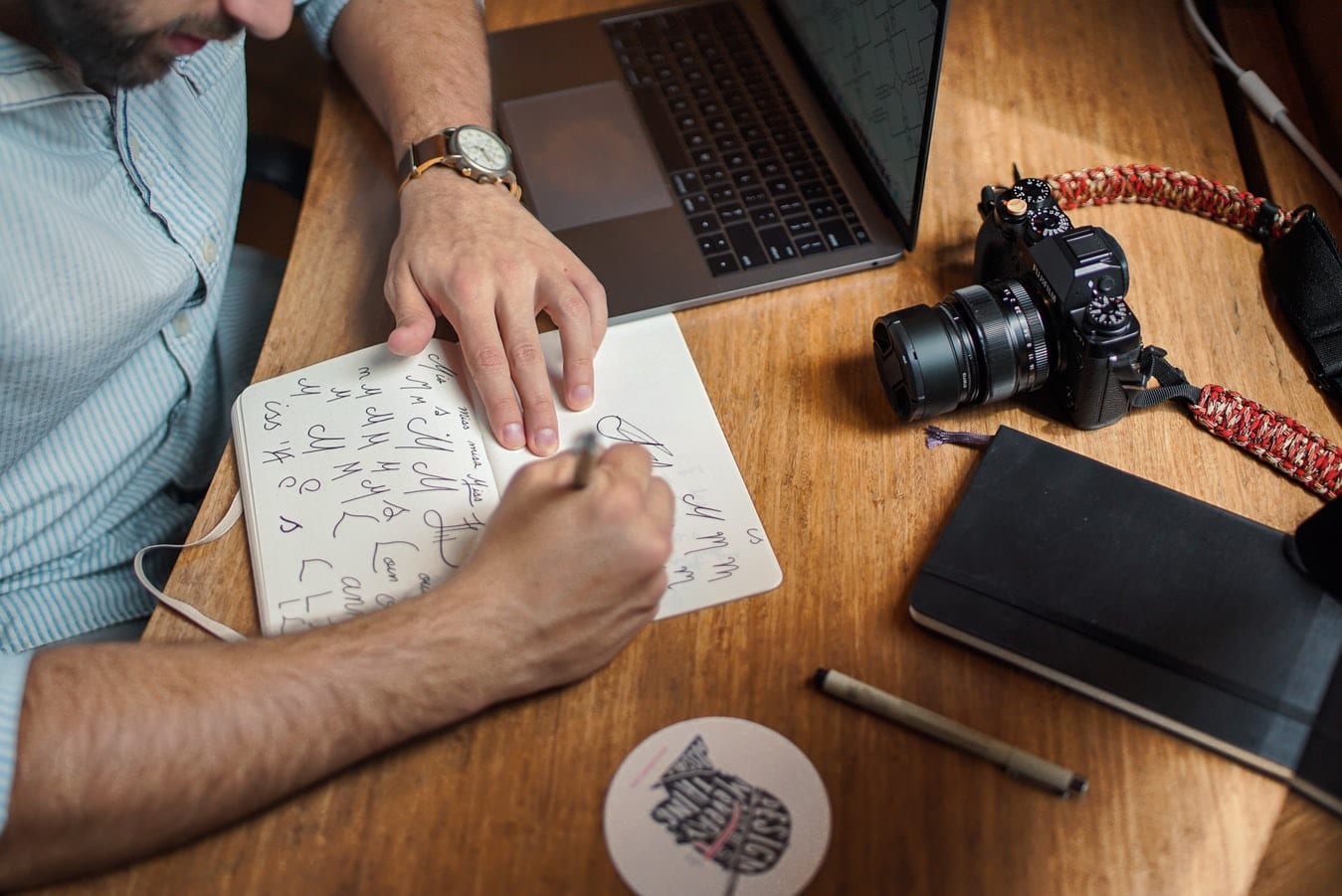 a man is sitting at a table with a laptop and a camera .