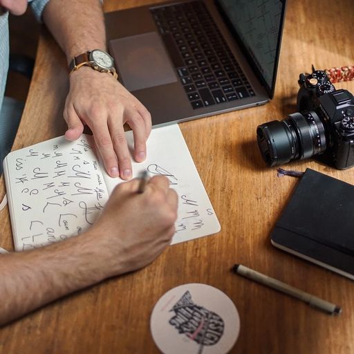 a man is sitting at a table with a laptop and a camera .