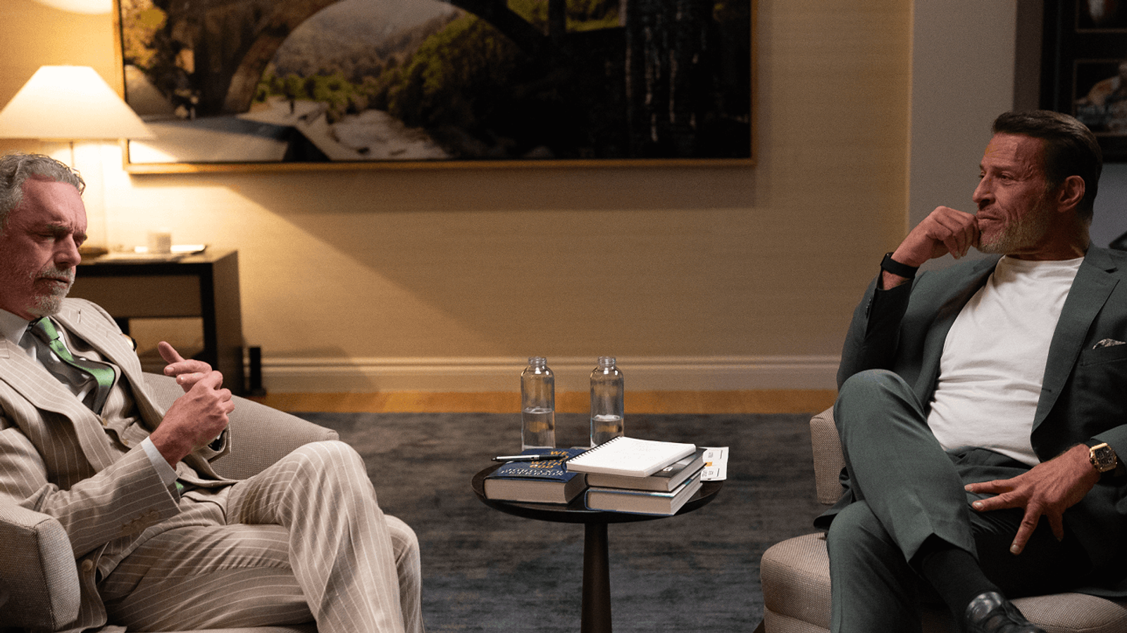 a man in a suit sits next to another man in a chair