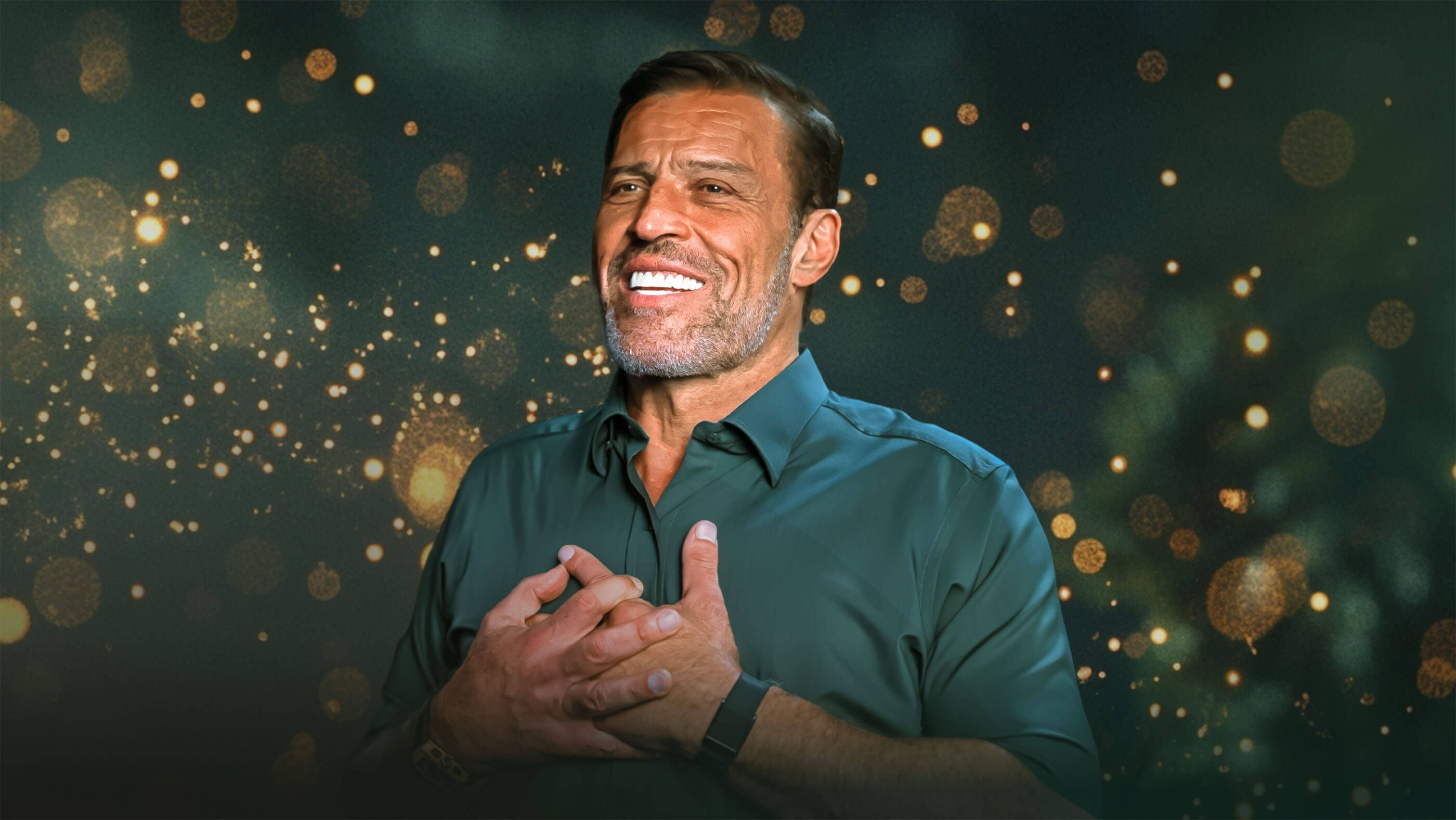 Tony Robbins smiling with his hands clasped over his chest, against a dark background with golden bokeh lights.