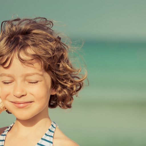 a little girl is listening to a sea shell on the beach .