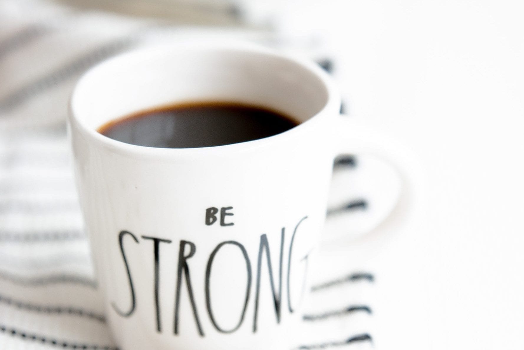 a cup of coffee with the words `` be strong '' written on it .