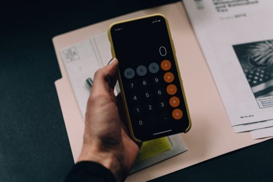 a person is holding a cell phone with a calculator on it .
