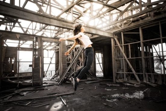 a woman is jumping in the air in an abandoned building .