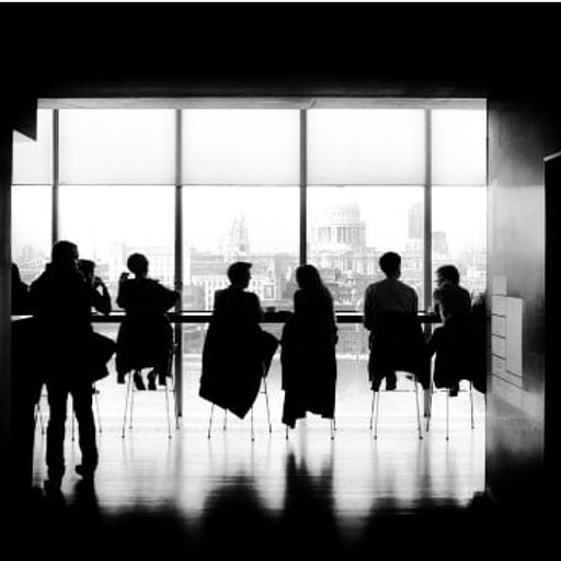 a group of people are sitting at tables in front of a large window .