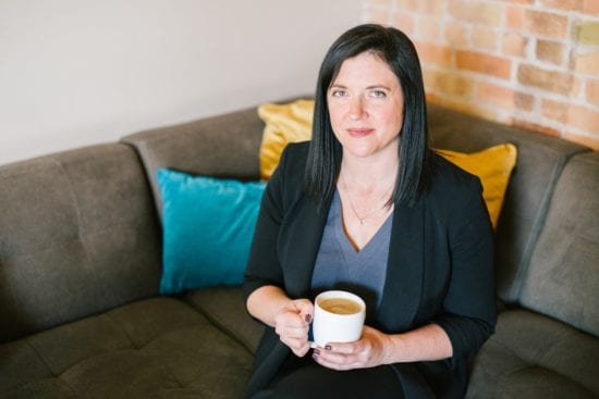 a woman is sitting on a couch holding a cup of coffee .