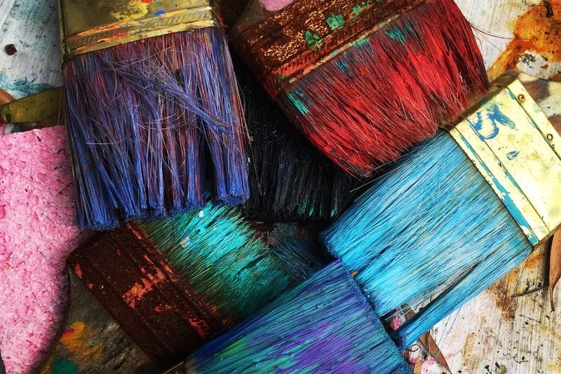 a bunch of paint brushes are stacked on top of each other on a table .