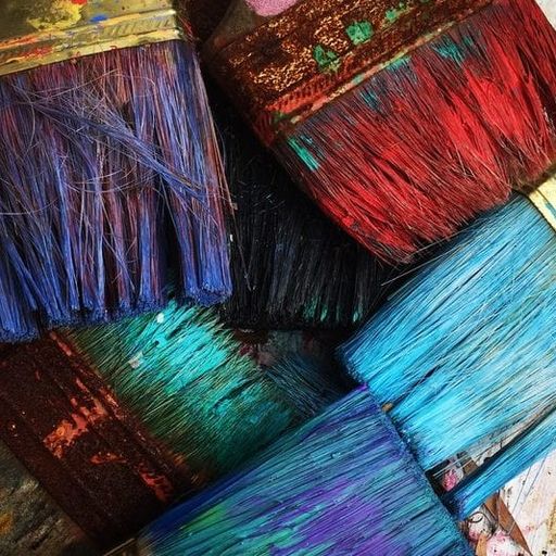 a bunch of paint brushes are stacked on top of each other on a table .