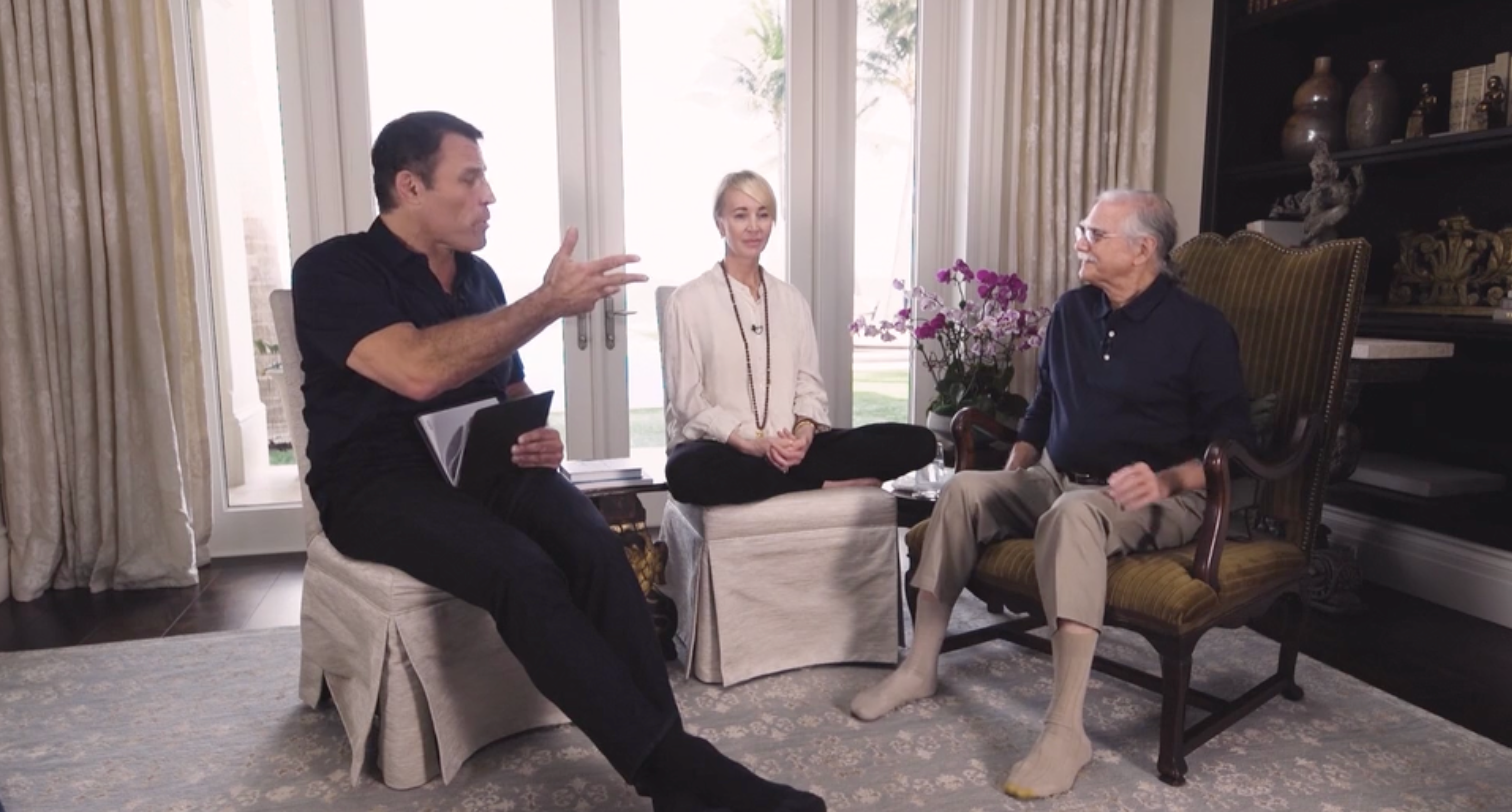 two men and a woman are sitting in chairs in a living room