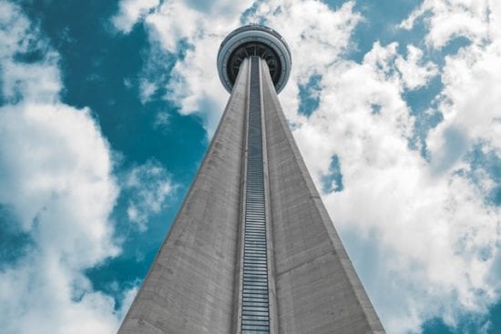 looking up at the cn tower in toronto against a blue sky with clouds .
