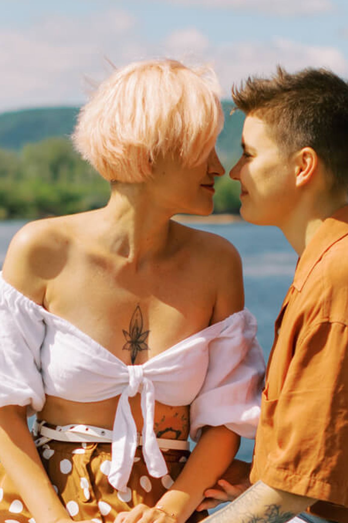 Deux personnes s'embrassent devant un lac.