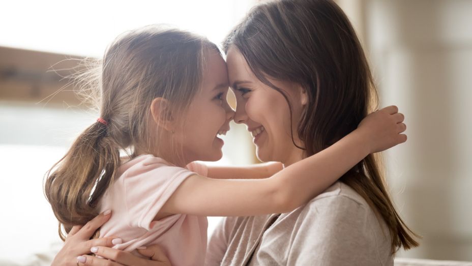 a woman and a little girl are hugging and touching their noses .