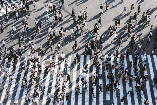 a large group of people are walking across a zebra crossing .