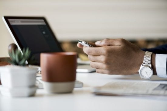 a man is sitting at a table using a cell phone .