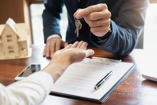 a man is giving a woman a set of keys while signing a contract .