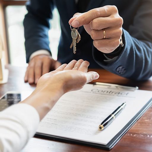 a man is giving a woman a set of keys while signing a contract .