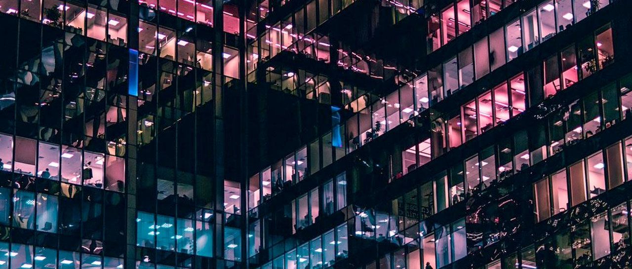 a tall building with lots of windows is lit up at night .