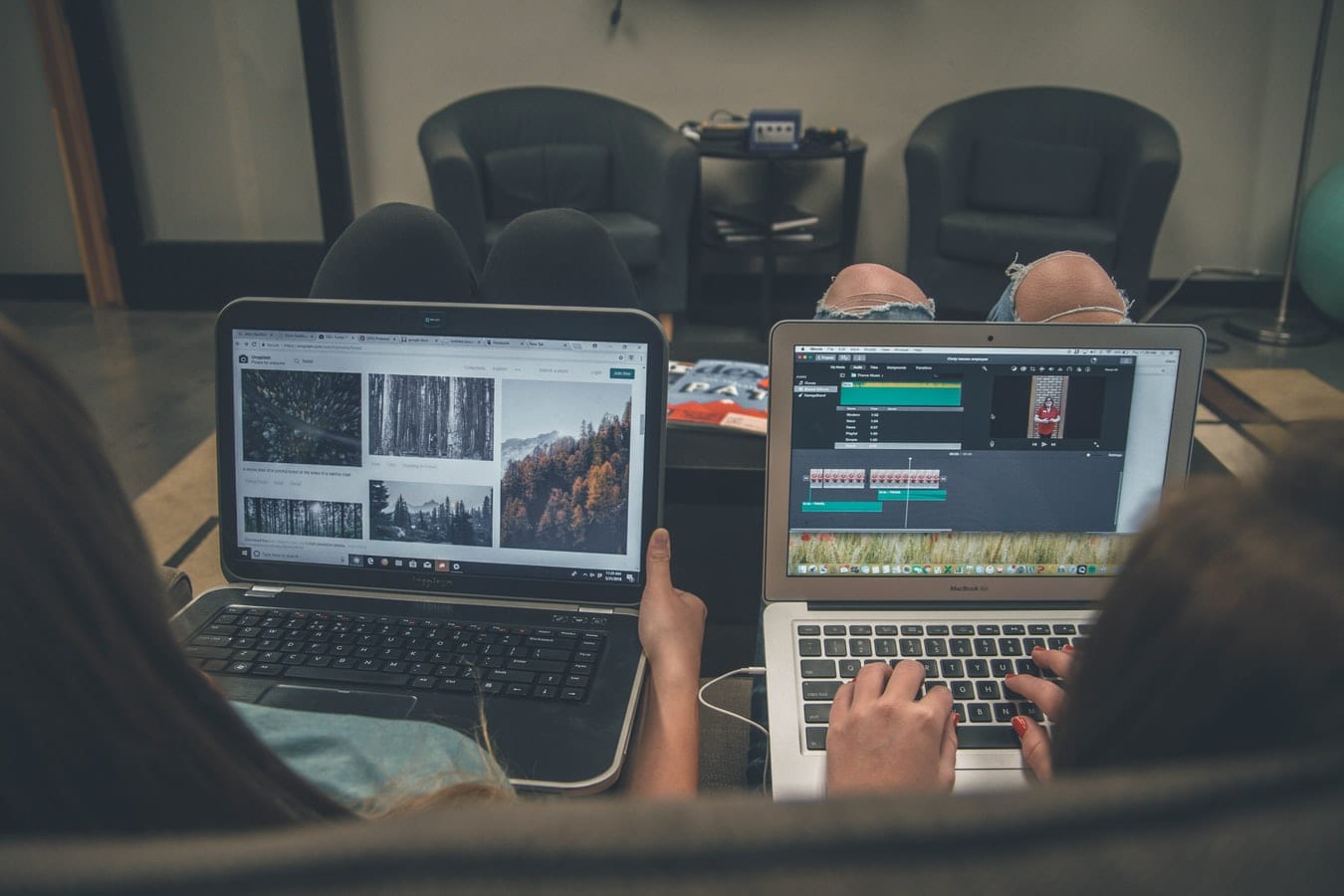 two people are sitting on a couch using laptops .