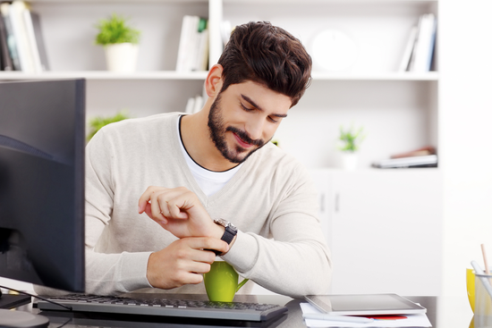 a man sitting at a desk looking at his watch