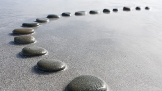 a row of rocks sitting on top of a sandy beach .