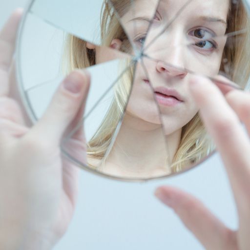 a woman is looking at her reflection in a broken mirror .
