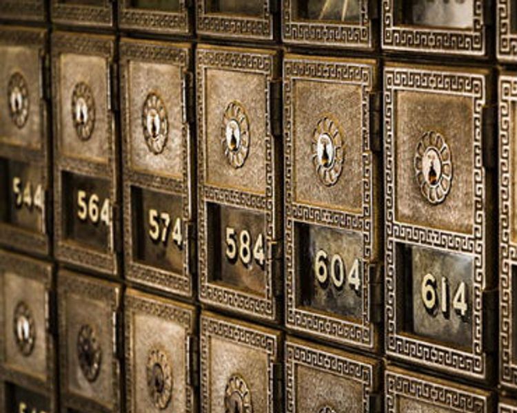 a row of metal safes with numbers on them in a bank .