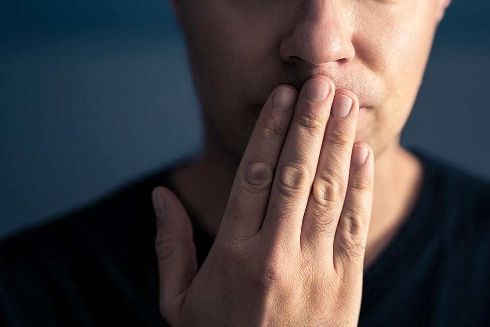 Man covering mouth with hand.