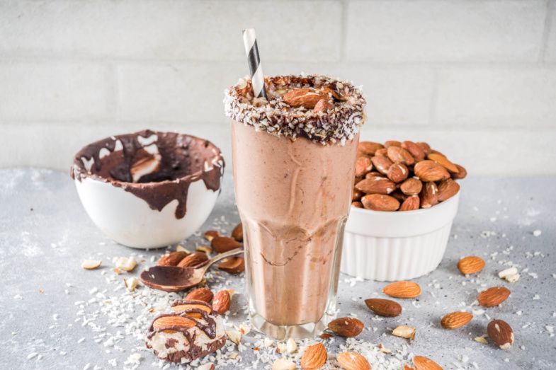 a chocolate milkshake with almonds and chocolate sauce on a table .