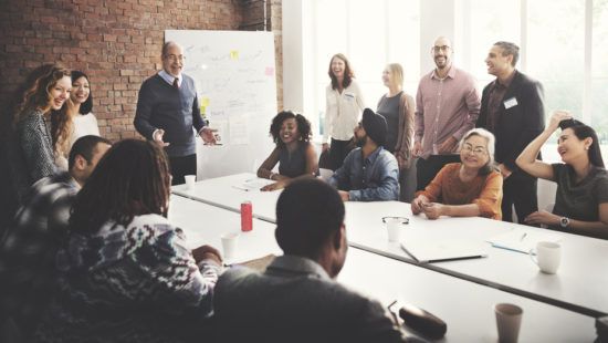 a group of people are sitting around a long table having a meeting .