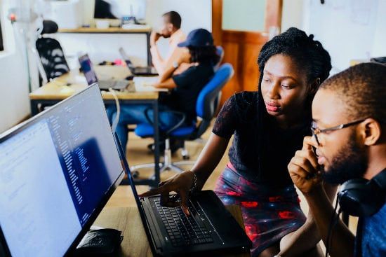 a man and a woman are looking at a laptop computer .