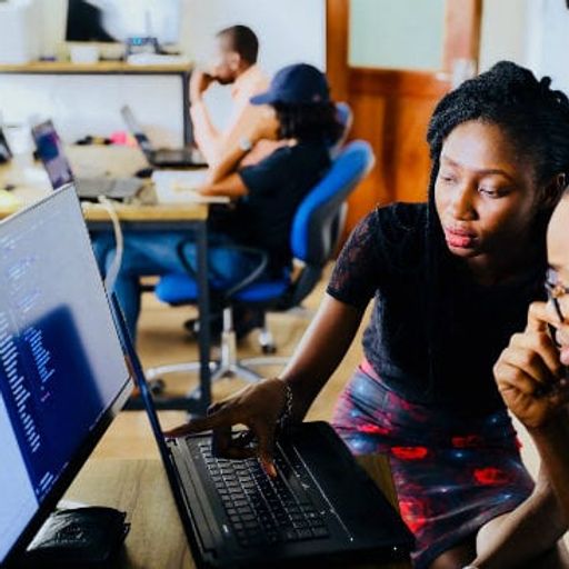 a man and a woman are looking at a laptop computer .