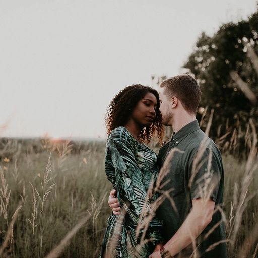 a man and a woman are standing in a field of tall grass .