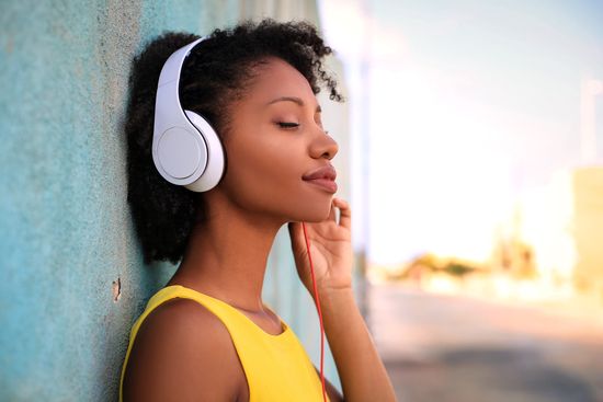 a woman wearing headphones is leaning against a wall .