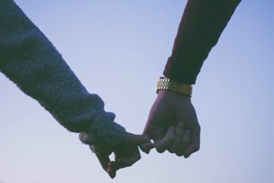 a man and a woman are holding hands against a blue sky .