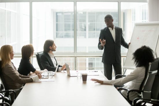 a man is giving a presentation to a group of people in a conference room .