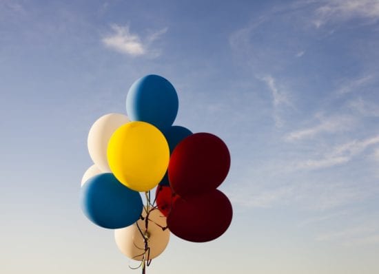 a bunch of colorful balloons are flying in the sky .