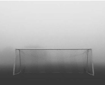 a black and white photo of a soccer goal in the fog .