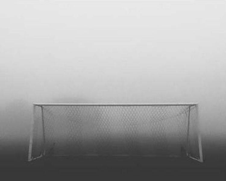 a black and white photo of a soccer goal in the fog .