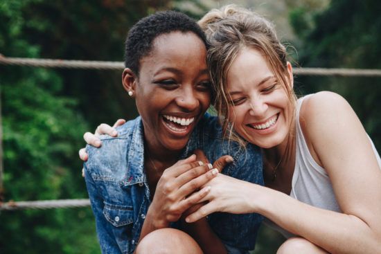 two women are sitting next to each other and laughing .